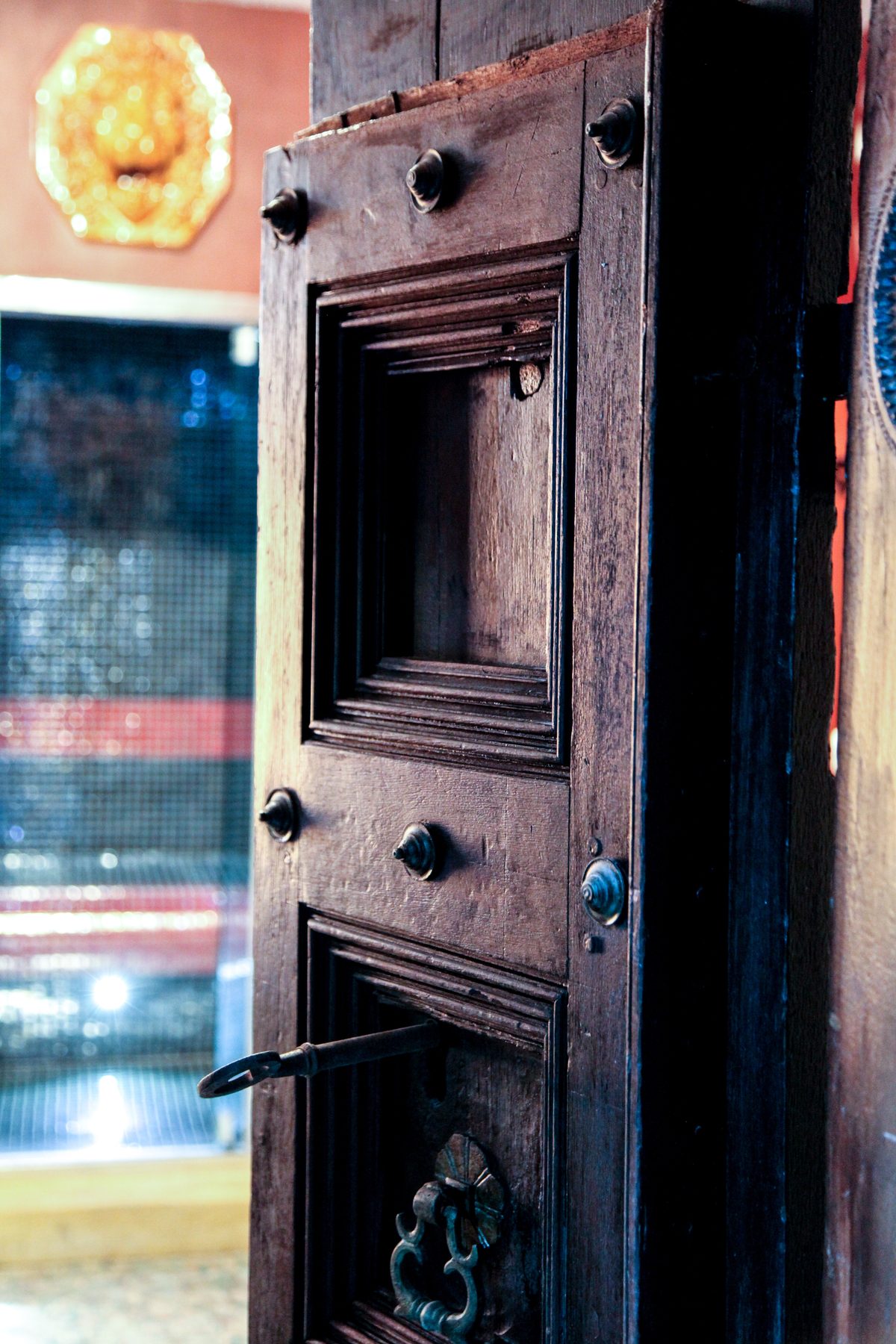 Une porte ancienne cloutée, entrouverte sur la pièce voisine