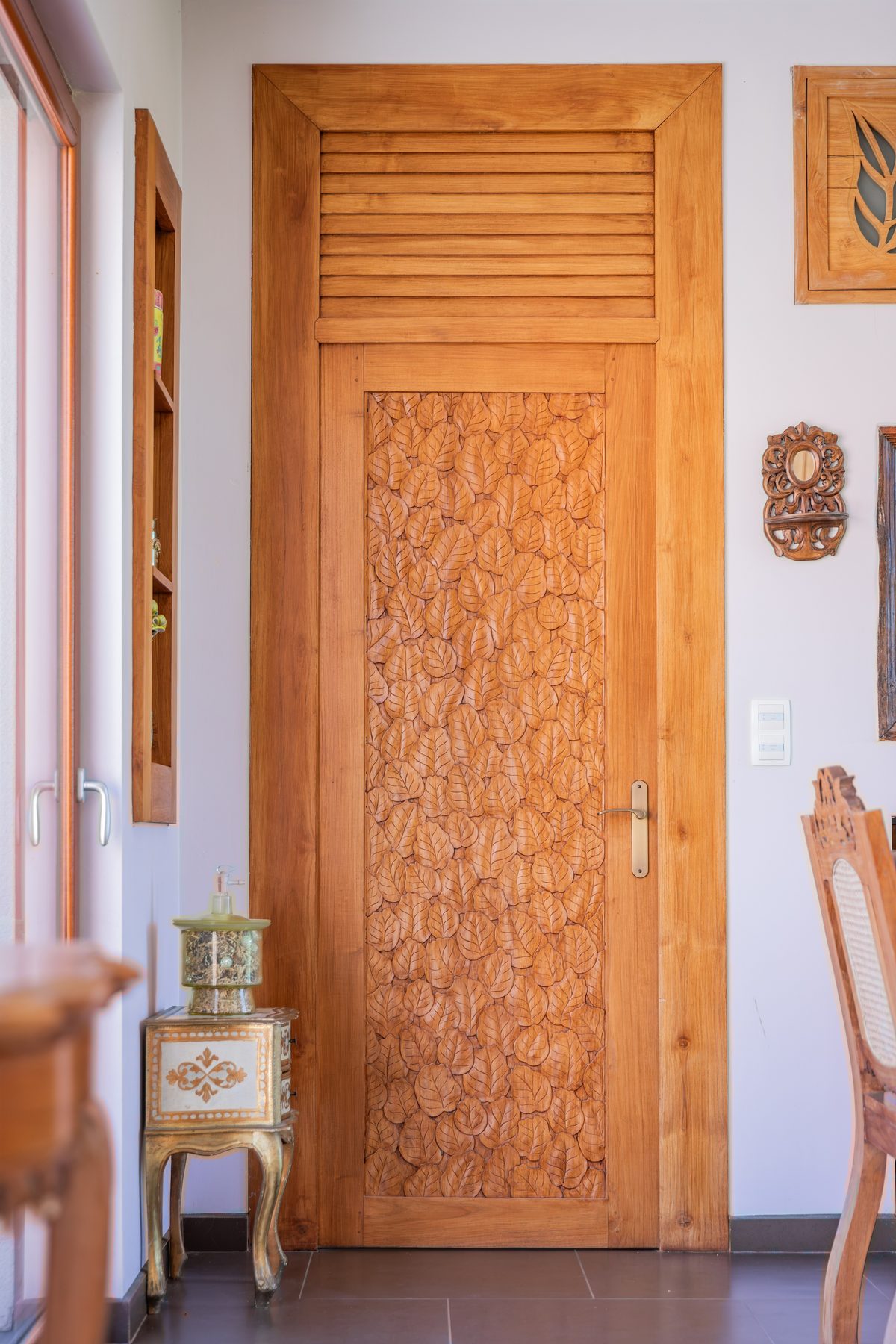 La porte de teck sculptée de feuilles, dans le couloir des suites
