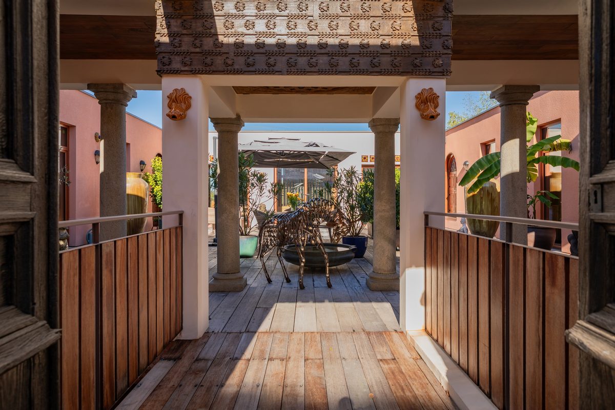 Le passage d'entrée couvert, son linteau sculpté et son plancher de teck, ouvert sur le patio