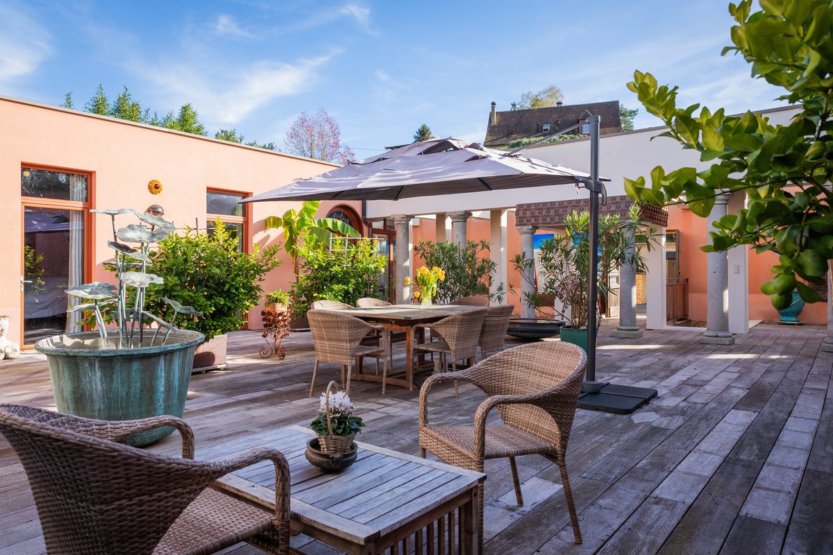 Le patio et sa table sous le parasol, entre les murs ocre
