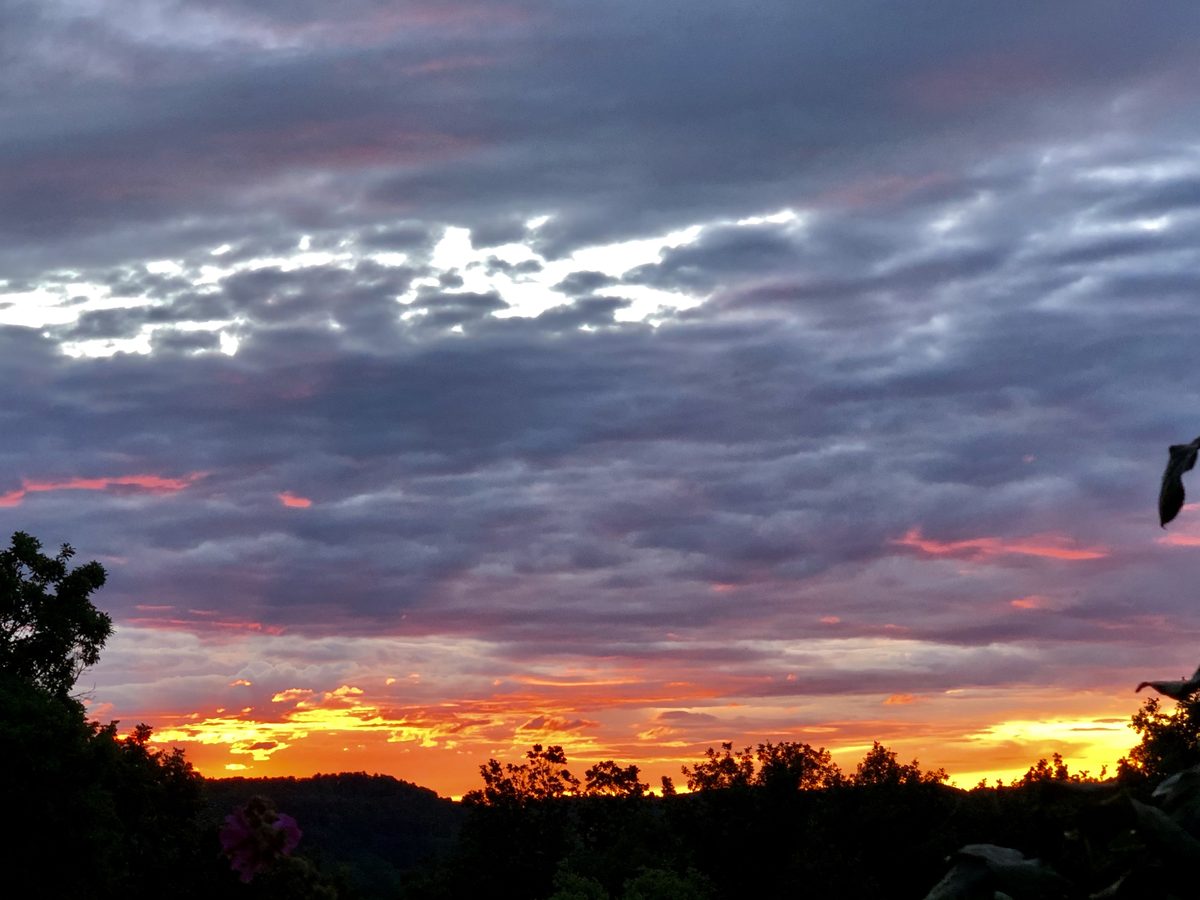 Le couchant orange sur les collines, sous un ciel de nuages