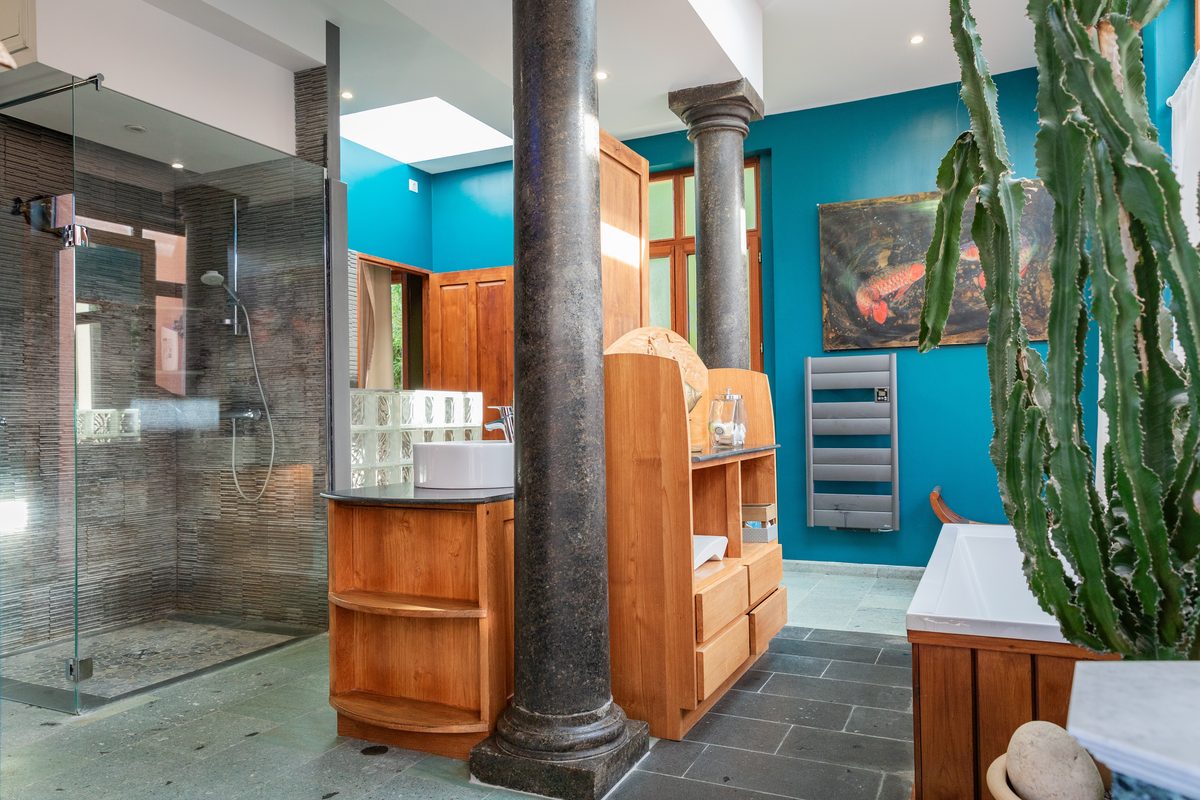 La salle de bains, sa colonne de granit et ses parois de verre sur un sol d'ardoise
