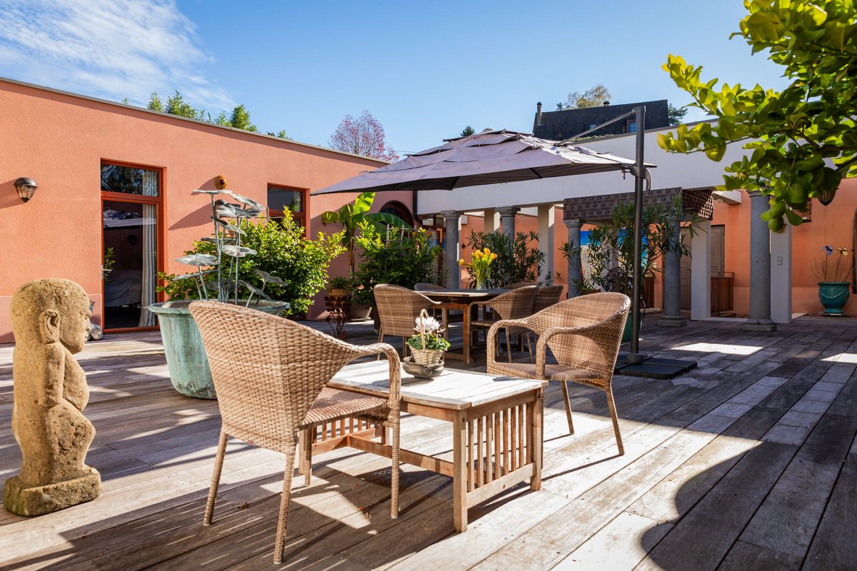 Le patio et ses fauteuils de rotin, à l'ombre du parasol