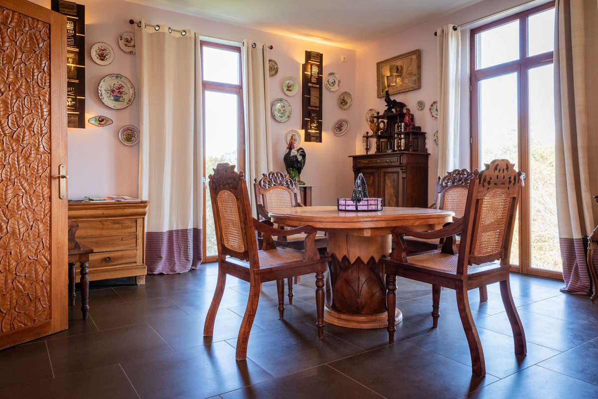 La salle à manger, sa table ronde en teck sculpté et ses faïences anciennes